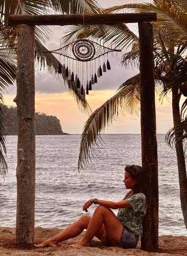 a woman sitting on the beach looking at the ocean at El Fin del estres Sapzurro in Sapzurro