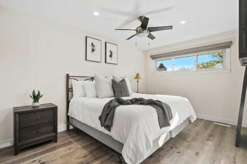 a white bedroom with a bed and a ceiling fan at Nineteen55 4BR Parkside Home in Central Red Deer in Red Deer