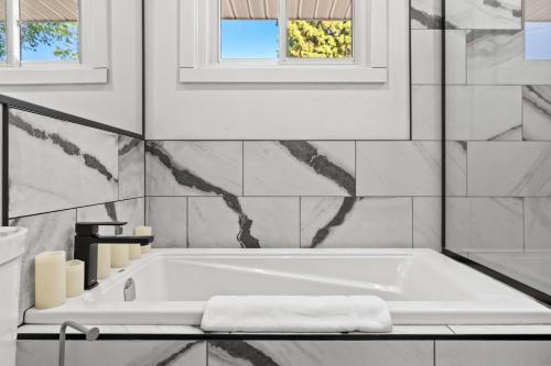 a white bath tub in a bathroom with a window at Nineteen55 4BR Parkside Home in Central Red Deer in Red Deer
