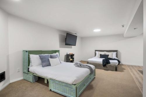 a bedroom with two beds and a flat screen tv at Nineteen55 4BR Parkside Home in Central Red Deer in Red Deer