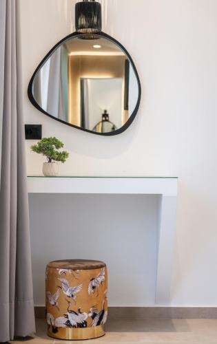 a mirror above a table with a plant and a stool at Marea Luxury Suites in Koríthion
