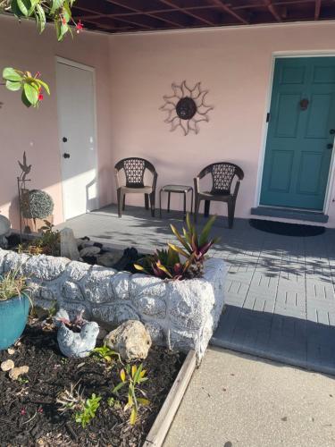 two chairs and a table on a porch with a door at Pink house in Fort Myers
