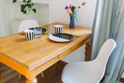 a wooden table with two white chairs and a table with flowers at Paradiesvogel - Zentral gelegenes Apartment in Paderborn Zentrum in Paderborn