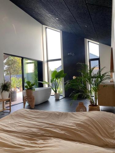 a bedroom with a large bed and a tub and plants at Villa med jacuzzi in Hørning