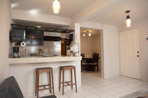 a kitchen with a counter and stools in a room at Departamento Carrera in San José de Malpaso