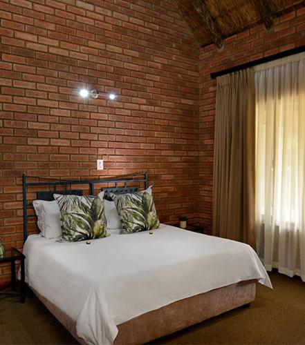a bedroom with a large bed in a brick wall at Monateng Safari Lodge by MyResorts in Wallmannstal