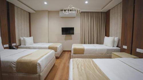 a hotel room with two beds and a tv at Quaint Hotel Erbil in Erbil