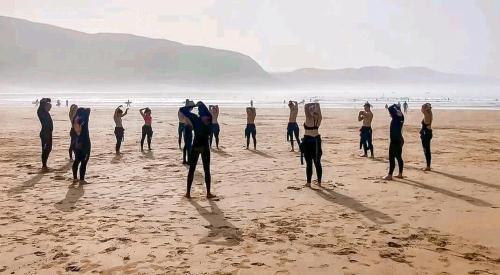 a group of people standing on a beach at Idriss Tamraght Surfhostel in Taghazout