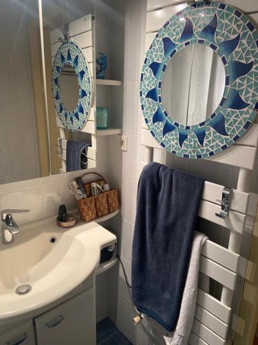 La salle de bains est pourvue d'un lavabo, d'un miroir et d'une serviette. dans l'établissement les Lucioles, à Thonon-les-Bains