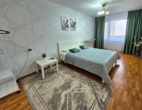 a bedroom with a bed and a table in it at 1 к квартира в Центре Мухита д 128 in Uralsk