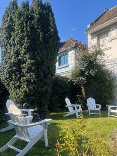 three white chairs sitting in the grass in front of a house at Hotel Du Croisé in Marcq-en-Baroeul