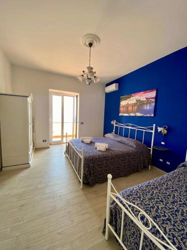 a bedroom with two beds and a blue wall at Holiday House ROSANNA in Conca dei Marini