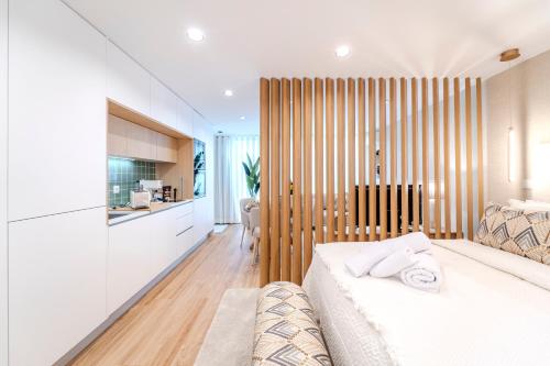 a bedroom with a white bed and a kitchen at Seventy Four House in Braga