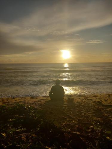 a man sitting on the beach watching the sunset at Vivez comme nous chez nous in Sambava