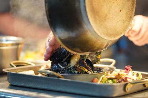 a person is cooking food in a pan at The Angel Inn in Thirsk