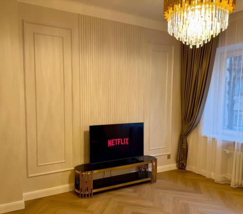 a living room with a tv and a chandelier at KR Apartment Kaunas in Kaunas