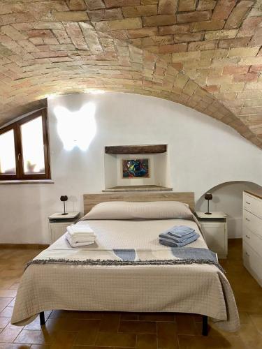 a bedroom with a large bed with a stone wall at Appartamento La Corte di Trevi in Trevi