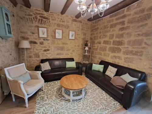 un salon avec un canapé en cuir et une table dans l'établissement La Demeure du Rempart - Sarlat Centre historique, à Sarlat-la-Canéda