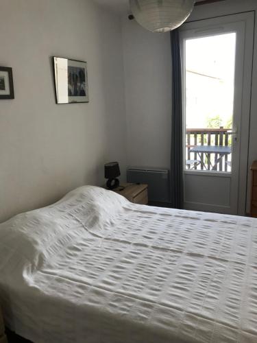 - un lit blanc dans une chambre avec fenêtre dans l'établissement Lou pastre, à Saintes-Maries-de-la-Mer