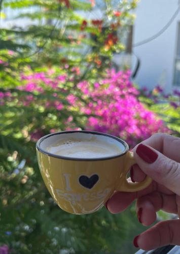 a person holding a cup of coffee in front of flowers at Apartamento em Praia do Francês in Praia do Frances