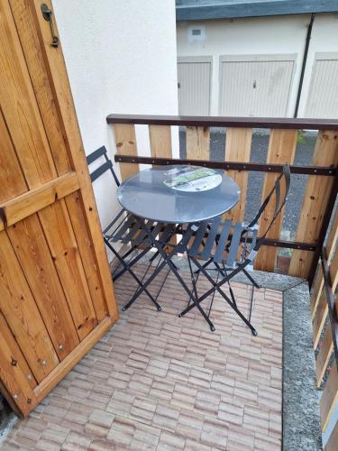 a table and chair on a balcony next to a wooden door at Cosy Brosso in Brosso