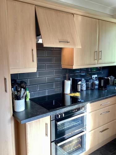 a kitchen with black counter tops and wooden cabinets at Lorton Villa with a Log Burner in Saint Helens