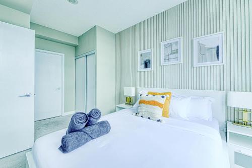 a bedroom with a large white bed with towels on it at RivetStays - The Parade 2 in Toronto