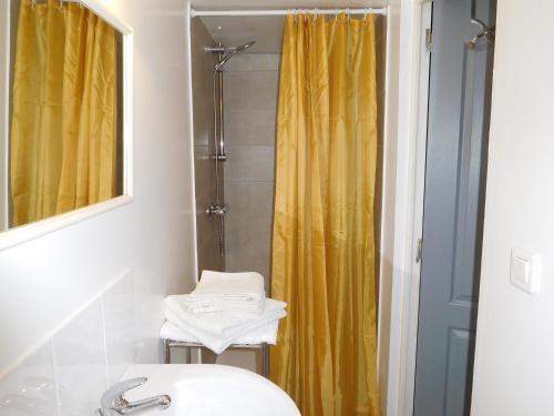 La salle de bains est pourvue d'un rideau de douche jaune et d'un lavabo. dans l'établissement Rural Holiday Cottage with private pool, à Saint-Blancard