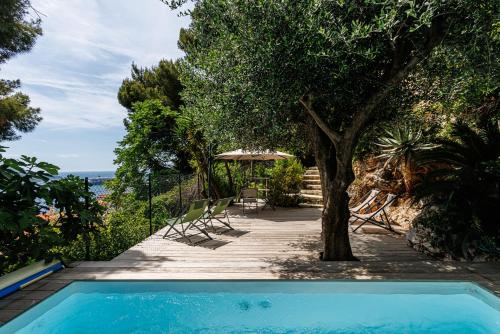 - une piscine avec une table, des chaises et un arbre dans l'établissement VILLA CRUG HYWEL - VILLEFRANCHE-SUR-MER, à Villefranche-sur-Mer