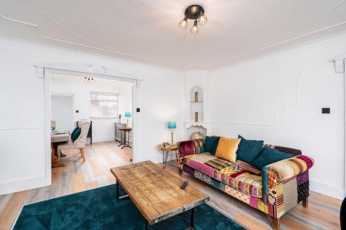 ein Wohnzimmer mit Sofa und Tisch in der Unterkunft Chic 3 BR Home with Balcony & Free Parking in Leeds