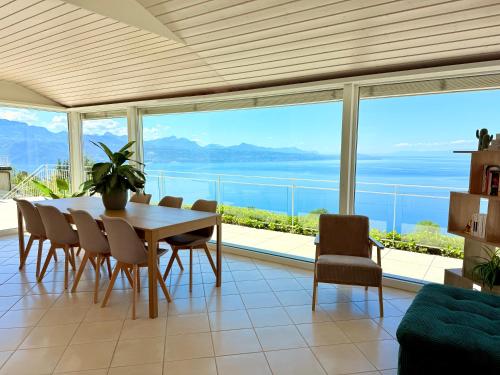 a dining room with a table and chairs and a large window at Villa Lavaux in Grandvaux
