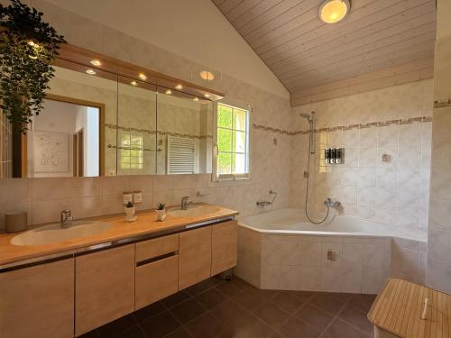 a bathroom with two sinks and a tub and a mirror at Villa Lavaux in Grandvaux