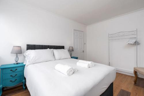 a bedroom with a large white bed with towels on it at Chic 3 BR Home with Balcony & Free Parking in Leeds