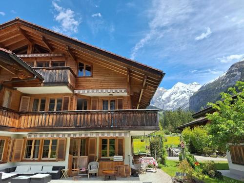 a wooden house with a balcony and mountains in the background at Apartment Haus Europa by Interhome in Kandersteg