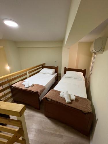 two beds in a small room with a lamp at Saranda View Apartments in Sarandë