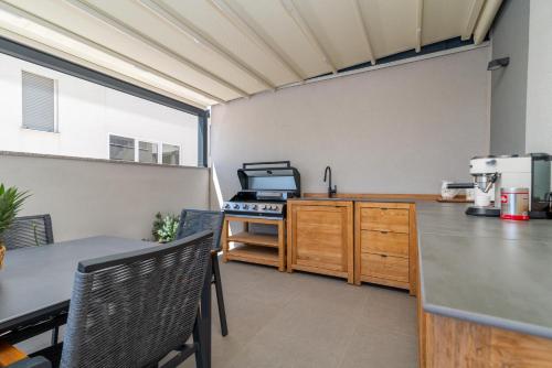 a kitchen with a stove and a counter with chairs at Apartman Pax in Podstrana