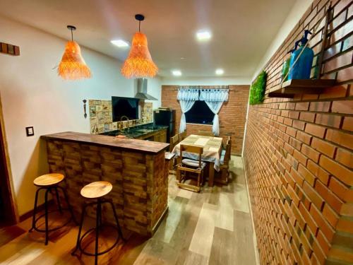 a kitchen with a brick wall and two bar stools at Cabaña Premium Ñakurutu de La Mala Junta in Atyrá