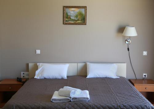 a bed with two towels and a picture on the wall at Hotel Sea Breeze in Sitia