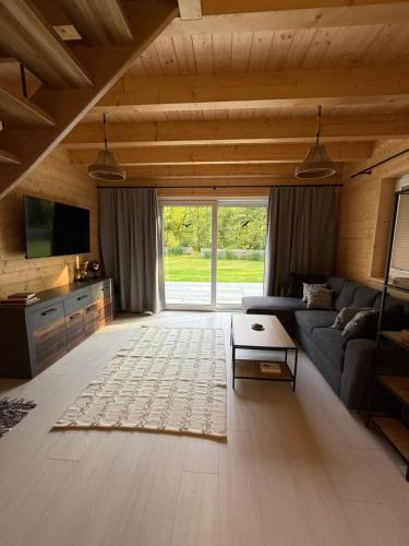 a living room with a couch and a tv at Domy nad Strugą - jacuzzi, las, wieś, rowery, kajaki 