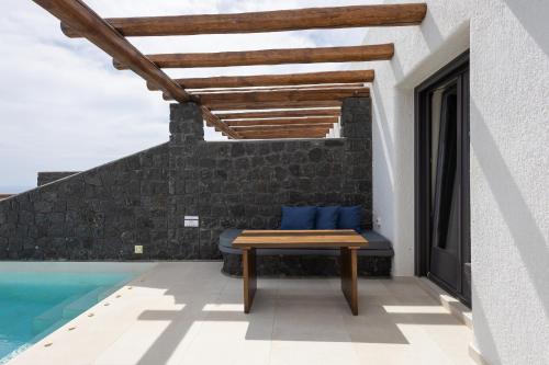 a patio with a bench next to a swimming pool at Brilliance Suites in Imerovigli