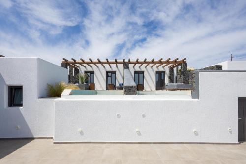 a white villa with a swimming pool in front of a house at Brilliance Suites in Imerovigli