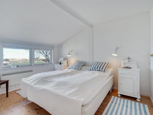 a white bedroom with a large white bed and a window at Holiday Home Githe - from the sea by Interhome in Hals