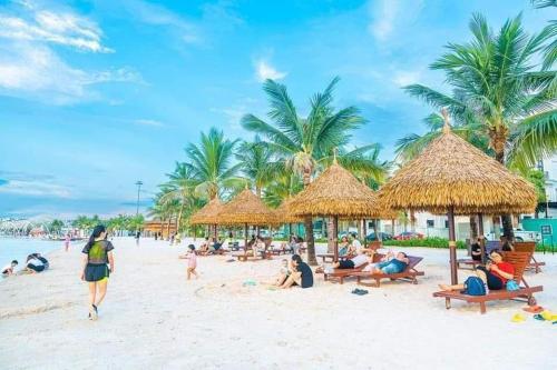 a group of people on a beach with straw umbrellas at Studio Vinhomes Ocean Park in Gia Lâm Pho
