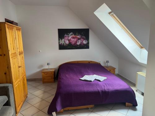 a bedroom with a purple bed in a attic at Elíxir Apartman Hajdúszoboszló in Hajdúszoboszló