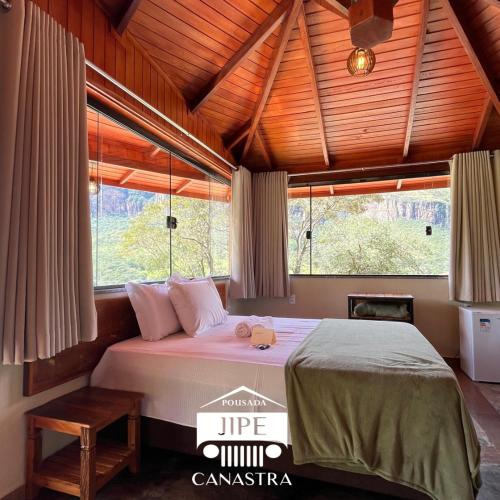 a bedroom with a large bed in a room with windows at Pousada Jipe Canastra in Capitólio