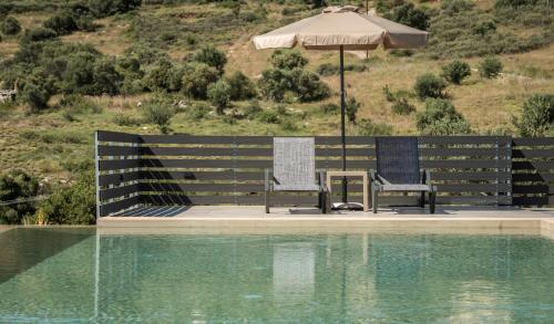 two chairs and an umbrella next to a swimming pool at Marea Luxury Suites in Koríthion