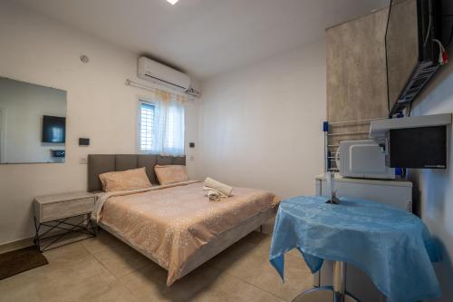 a bedroom with a bed and a tv and a table at אדום 179, דירות נופש in Eilat