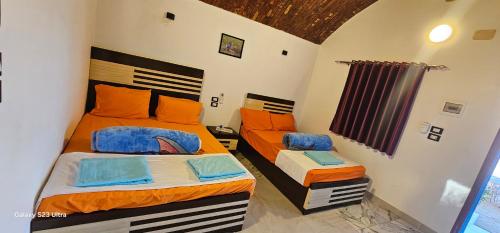 a bedroom with two beds with orange and blue pillows at Hannag Island in Aswan