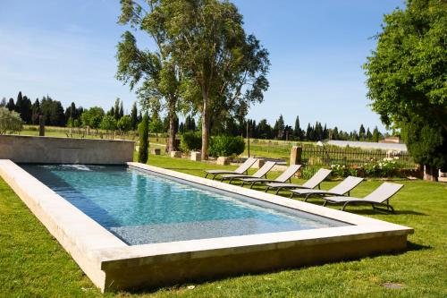- une piscine avec des chaises longues dans un champ dans l'établissement Mas des Oliviers, à Maillane
