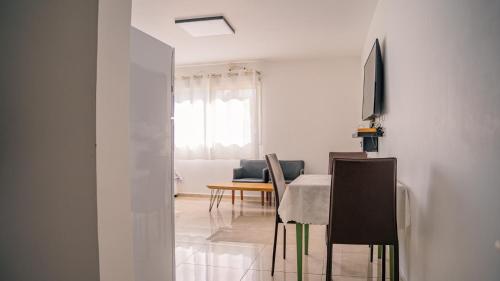 a white living room with a table and a television at אדום 179, דירות נופש in Eilat